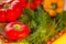 Several bell peppers along with dill greens on a wicker stand