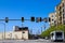 Several black and yellow traffic signals on a pole surrounded by buildings, lush green trees and cars in Atlanta