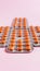 Several blisters with medicine pills on pink background. Rows of tablets, capsules