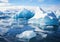 Several blue icebergs in blue ocean water against the sky