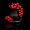 Several bunches of red currants in a black cup on a black background