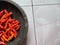 several chilies on a traditional mill made of solid stone isolated on white background -- pestle.