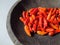 several chilies on a traditional mill made of solid stone isolated on white background -- pestle.