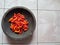 several chilies on a traditional mill made of solid stone isolated on white background -- pestle.