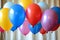 Several colorful balloons are floating in the air against a clear blue sky, Assorted latex balloons for a surprise birthday party