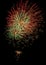 Several colorful fireworks exploding in the dark sky in the middle of the night. The explosions light the sky creating colorful