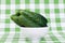 Several cucumbers in a white bowl on a green checkered napkin, s