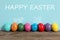 Several eggs with drawn faces and ears as Easter bunnies among others on wooden table against light blue background