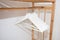 Several empty white hangers on the wooden carrying clothes hangars lined up