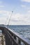 Several fishing rods leaning on fence on pier