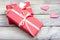 Several gifts wrapped in pink paper and tied with a white ribbon on a light wooden table.