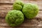 Several green osageorange on wood closeup