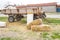 Several hay bales next to the tractor trailer and country houses