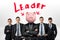 Several identical businessmen stand clothe to each other around one man with a piggy bank head under the Leader word. T