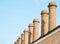 Several industrial brick chimneys without smoke stand next to each other in perspective against a clear blue sky