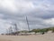 Several jacked sail boats on the beach in front of a dune.