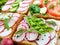 Several kinds of sandwiches with vegetables: radish, tomatoes, cucumber, arugula on crispy toast