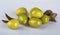 Several large beautiful green olives with olive tree leaves isolated on a glossy light background with reflection.