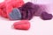 Several multi-colored felted woolen hearts on pink background