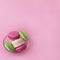 Several multi-colored macarons in a glass plate on a square pink background