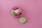 Several multicolored macarons in a glass plate on a pink background