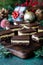 Several Nanaimo bars on a wooden board with Christmas decorations in behind.