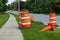 Several orange barrels and traffic cones protecting some road repair