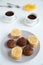 Several pieces sponge cakes with cream on gray plate with cups of tea on a white concrete background close up.