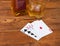 Several playing cards, bottle and glass whisky on rustic table
