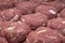 Several raw minced meat cutlets lie in rows