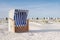 Several roofed wicker beach chairs on empty sand beach on North Sea coast. Beach equipment at holiday resorts