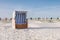 Several roofed wicker beach chairs on empty sand beach on North Sea coast. Beach equipment at holiday resorts