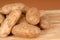 Several russet potatoes piled on a cutting board