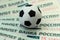 Several Russian banknotes for one thousand rubles are under a souvenir soccer ball. The concept of spending money on the champions