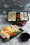 Several sets of sushi with wasabi and soy sauce in plastic packaging on a light gray background. Delicious rolls with shrimp,