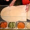 Several sheets of pita bread on the work surface and a bowl with already prepared and chopped vegetables.