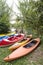 Several single and double kayaks on the riverside