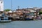 Several small white and blue fishing boats and buildings from the river`s or ferry`s point of view. Location Brejo Grande, Brazi