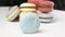 Several times in row blue macaron rolling on a white table.