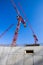 Several tower cranes over a newly erected concrete wall. Low angle view looking up