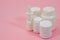 Several types of white medicine bottles on pink background