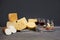Several varieties of cheese on a wooden board, glasses with red wine and skewers with appetizers