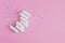 Several white sanitary tampons on a pink background.