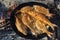 Several whole fish frying in a pan on open fire