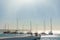Several yachts in a row are parked at the pier. Blue sky and sea in the background. Sunlight and glow on the water