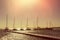 Several yachts in a row are parked at the pier. Sunset sky and sea in the background. Sunlight and glow on the water