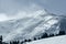 Severe winter weather blows snow over mountain peak