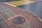 Sewer cast iron manholes on sidewalk. Wet metal is covered with yellow autumn leaves after rain