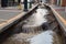 sewer water spilling out of the broken pipes onto the sidewalk