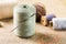 Sewing concept. Thread spool with needle with other spools on canvas background